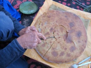 Berber man cutting traditional Berber pizza Saf Saf Oasis Morocco_Source NOSADE